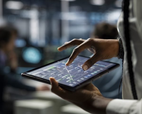 Close up of data center computer scientist using tablet, deploying servers and network hardware. IT specialist in server farm using device to manage large scale IT infrastructure